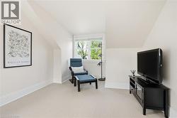 Carpeted room with sloped ceilings, white baseboards, and a double-hung window - 