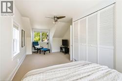 Carpeted room with a multi-pane window, sloped ceilings, and a ceiling fan with integrated lighting - 