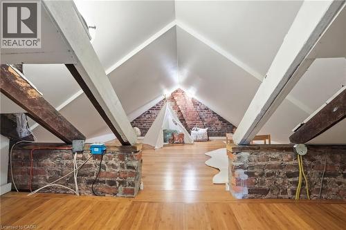 Attic space featuring pitched white ceilings, exposed brick walls, light wood-finish flooring, and structural wood beams - 314 Hess Street S, Hamilton, ON - Indoor Photo Showing Other Room