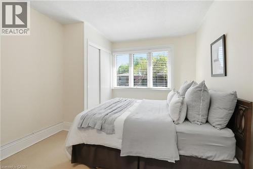 Bedroom featuring a window with horizontal blinds, light-colored carpeting, white baseboards, and a built-in closet with sliding doors - 314 Hess Street S, Hamilton, ON - Indoor Photo Showing Bedroom