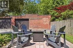 Paved patio area featuring a fire pit and a brick wall - 