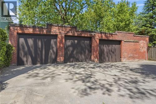 Three-stall brick garage with dark wood-finish doors and a paved driveway - 314 Hess Street S, Hamilton, ON - Outdoor