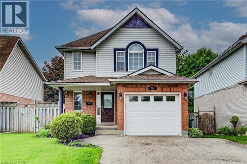 Two-story residence featuring a brick and siding facade, an attached garage with a panel door, a covered front entry, and mature landscaping - 702 Elgin Street N, Cambridge, ON - Outdoor