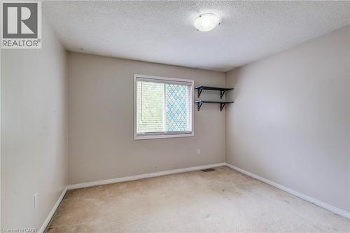 Neutral-toned room featuring a single window with blinds, wall-mounted shelving, and a ceiling-mounted light fixture - 702 Elgin Street N, Cambridge, ON - Indoor Photo Showing Other Room