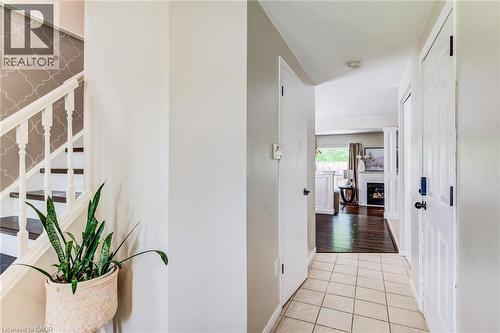Entryway featuring ceramic tile flooring, a staircase with wood-finish treads and white balusters, and a patterned accent wall - 702 Elgin Street N, Cambridge, ON - Indoor Photo Showing Other Room