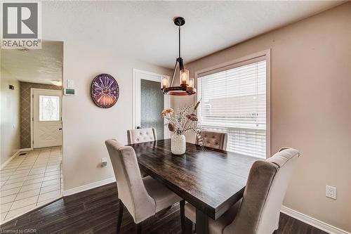 Dining area featuring wood-finish flooring, a contemporary chandelier, a large window with blinds, and neutral wall tones - 702 Elgin Street N, Cambridge, ON - Indoor Photo Showing Dining Room