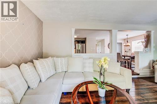 Living space featuring dark wood-finish flooring, a decorative accent wall, and architectural half-walls defining distinct areas - 702 Elgin Street N, Cambridge, ON - Indoor Photo Showing Living Room