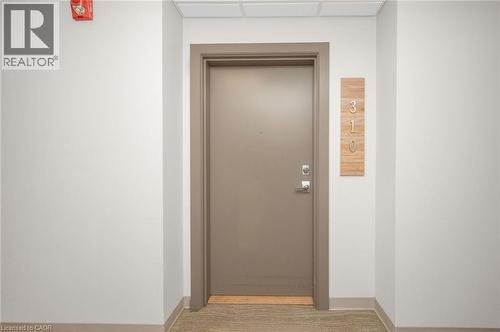 Entry door with satin nickel hardware, a wood-finish number plaque, and a recessed ceiling fire alarm - 10 Esplanade Lane Unit# 310, Grimsby, ON - Indoor Photo Showing Other Room