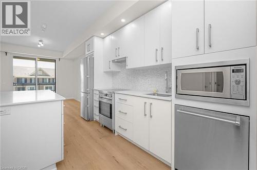 Contemporary kitchen featuring white cabinetry, stainless steel appliances, a white quartz countertop, and wood-finish flooring - 10 Esplanade Lane Unit# 310, Grimsby, ON - Indoor Photo Showing Kitchen With Upgraded Kitchen