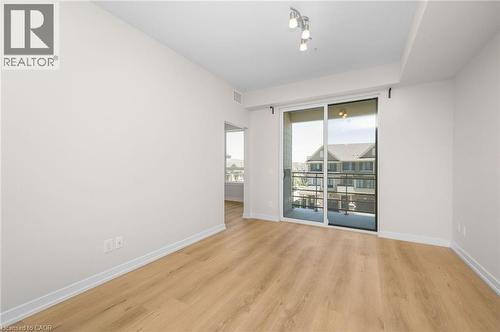 Bright living space featuring wood-finish flooring, white baseboards, and a sliding glass door leading to a balcony - 10 Esplanade Lane Unit# 310, Grimsby, ON - Indoor Photo Showing Other Room