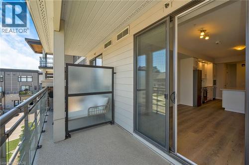 Balcony with clear glass railings, a frosted privacy screen, and a sliding glass door offering access to the interior - 10 Esplanade Lane Unit# 310, Grimsby, ON - Outdoor With Exterior
