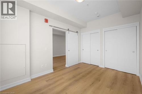 Bright room featuring wood-finish flooring, white walls, and a barn door entry - 10 Esplanade Lane Unit# 310, Grimsby, ON - Indoor Photo Showing Other Room