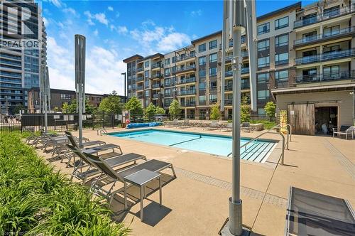Outdoor swimming pool with concrete decking, surrounded by modern multi-story buildings - 10 Esplanade Lane Unit# 310, Grimsby, ON - Outdoor With In Ground Pool