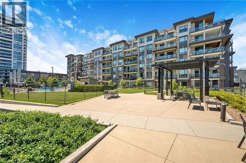 Expansive outdoor patio area featuring a modern pergola with seating, bordered by lush green landscaping and manicured lawns - 10 Esplanade Lane Unit# 310, Grimsby, ON - Outdoor