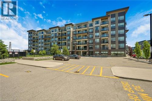 Contemporary multi-story building featuring a facade of varying tones, individual balconies with glass railings, and expansive windows - 10 Esplanade Lane Unit# 310, Grimsby, ON - Outdoor With Facade