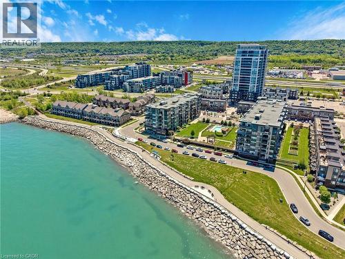 Waterfront complex featuring modern multi-story buildings, dedicated pedestrian pathways, and structured rock shoreline - 10 Esplanade Lane Unit# 310, Grimsby, ON - Outdoor With Body Of Water With View