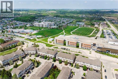 Aerial perspective showcasing the residential community with multiple townhome structures featuring light-colored facades and dark roofs - 619 Wild Ginger Avenue Unit# C15 & #C16, Waterloo, ON - Outdoor With View