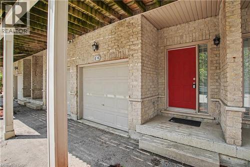 Front exterior featuring a vibrant red entry door, stone brick facade, and an integrated garage - 619 Wild Ginger Avenue Unit# C15 & #C16, Waterloo, ON - Outdoor With Exterior