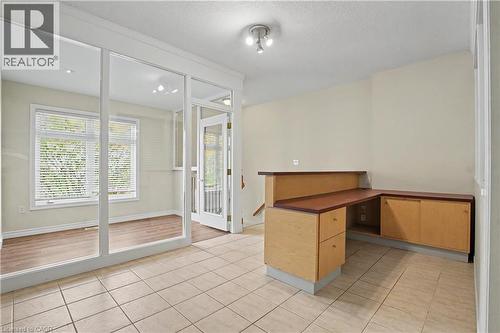 Tile flooring in main area, with a built-in desk featuring a wood-finish countertop and light wood-finish cabinetry - 619 Wild Ginger Avenue Unit# C15, Waterloo, ON - Indoor Photo Showing Other Room