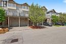 Townhome exterior featuring light-toned siding, a second-story balcony with wooden railings, and two ground-level garage doors - 619 Wild Ginger Avenue Unit# C15, Waterloo, ON  - Outdoor 