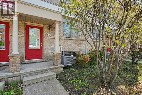 Stone veneer facade with a red entry door featuring a full-light insert - 619 Wild Ginger Avenue Unit# C15, Waterloo, ON - Outdoor