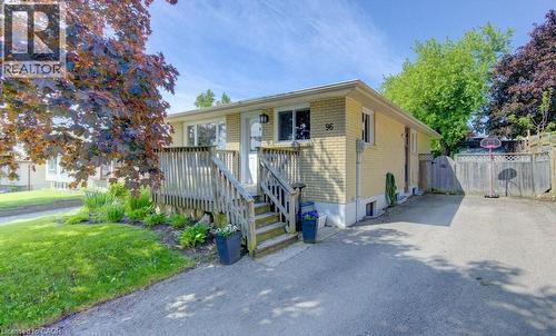 Brick exterior featuring a wood deck with stairs, established landscaping, and a paved driveway - 96 Scott Road, Cambridge, ON - Outdoor