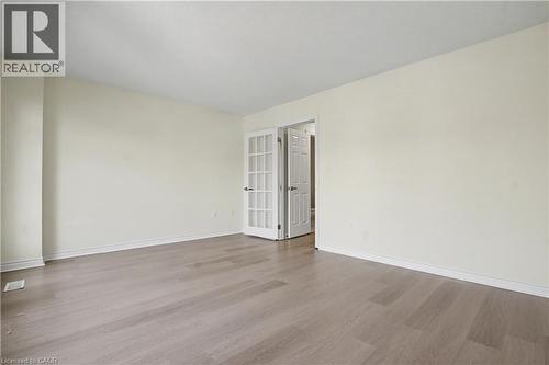 Spacious room featuring wood-finish flooring, white baseboards, and neutral wall paint - 619 Wild Ginger Avenue Unit# C16, Waterloo, ON - Indoor Photo Showing Other Room