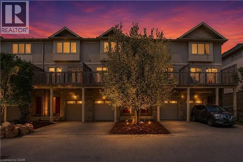 Contemporary townhome exterior featuring an elevated deck with wood railing, individual garage bays, and dedicated driveways - 619 Wild Ginger Avenue Unit# C16, Waterloo, ON - Outdoor