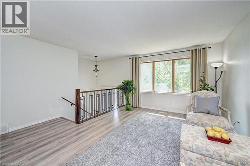 Open landing area featuring light wood-finish flooring, a contemporary black metal and wood balustrade, and a window with light-filtering drapes - 92 Pinemeadow Crescent, Waterloo, ON - Indoor Photo Showing Other Room