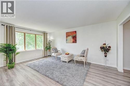Spacious room featuring light wood-finish flooring, a large multi-pane window with drapes, and white painted walls - 92 Pinemeadow Crescent, Waterloo, ON - Indoor