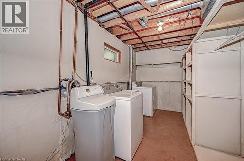 Utility area featuring white washer and dryer units, a water softener system, exposed ceiling joists, and built-in shelving - 92 Pinemeadow Crescent, Waterloo, ON - Indoor Photo Showing Laundry Room