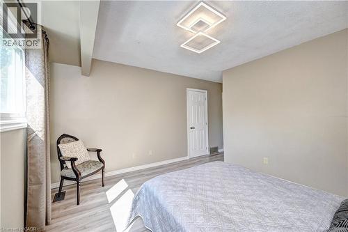 Spacious room featuring light wood-finish flooring, a contemporary flush-mount ceiling light fixture, and a window with natural light - 92 Pinemeadow Crescent, Waterloo, ON - Indoor Photo Showing Bedroom