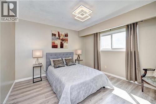 Bright room featuring wood-finish flooring, a contemporary ceiling light fixture, and a window with white framing - 92 Pinemeadow Crescent, Waterloo, ON - Indoor Photo Showing Bedroom