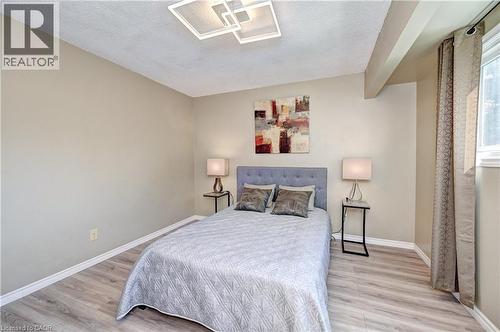 Neutral tone walls with wood-finish flooring, featuring a modern ceiling light fixture - 92 Pinemeadow Crescent, Waterloo, ON - Indoor Photo Showing Bedroom