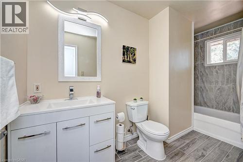 Bathroom featuring a white vanity with integrated sink, chrome faucet, and a rectangular mirror with an overhead curved light fixture - 92 Pinemeadow Crescent, Waterloo, ON - Indoor Photo Showing Bathroom