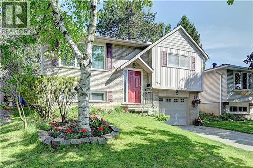 Split-level residence featuring a brick and siding exterior, an attached single-car garage, and a red front entry door with a covered porch - 92 Pinemeadow Crescent, Waterloo, ON - Outdoor