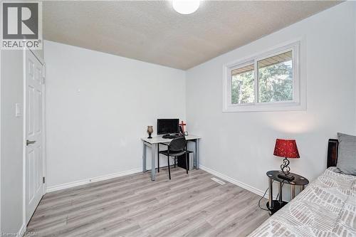 Bright interior room featuring light grey wood-finish flooring, white baseboards, and a white six-panel door - 92 Pinemeadow Crescent, Waterloo, ON - Indoor Photo Showing Bedroom