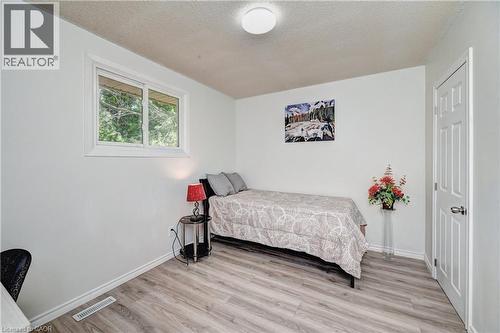 Bright room featuring a window with white trim, wood-finish flooring, white walls, and a white interior door - 92 Pinemeadow Crescent, Waterloo, ON - Indoor Photo Showing Bedroom