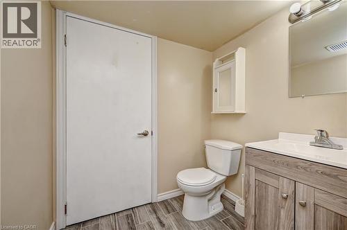 Bathroom featuring wood-look tile flooring, a white vanity with a laminate countertop, and an integrated rectangular sink - 92 Pinemeadow Crescent, Waterloo, ON - Indoor Photo Showing Bathroom