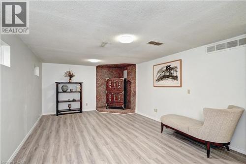 Spacious room featuring wood-finish flooring, white painted walls, and a brick feature wall - 92 Pinemeadow Crescent, Waterloo, ON - Indoor