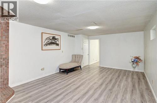 Spacious room featuring wood-finish flooring, a tile-clad architectural element, white painted walls, and ceiling-mounted lighting fixtures - 92 Pinemeadow Crescent, Waterloo, ON - Indoor