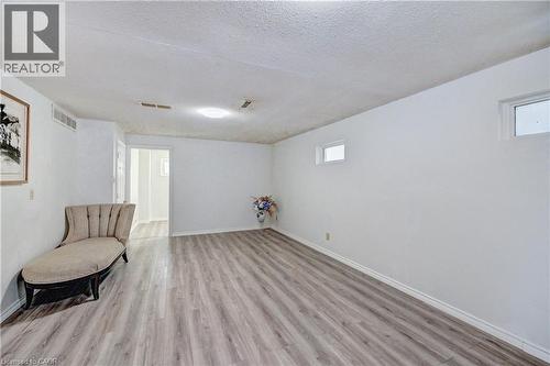 Spacious room featuring wood-finish flooring, white baseboards, and bright white walls - 92 Pinemeadow Crescent, Waterloo, ON - Indoor Photo Showing Other Room