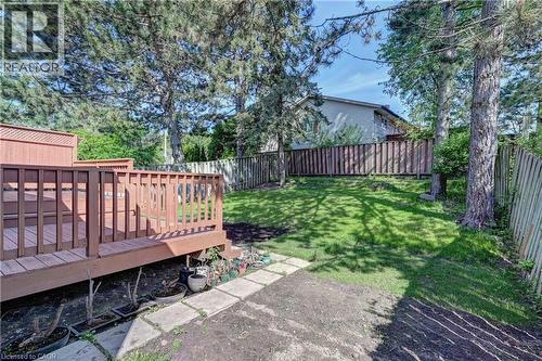 Expansive rear yard featuring a multi-level wood deck, manicured lawn, established trees, and perimeter fencing - 92 Pinemeadow Crescent, Waterloo, ON - Outdoor