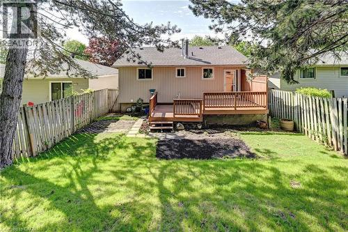 Expansive backyard featuring a wood deck, manicured lawn, and privacy fencing - 92 Pinemeadow Crescent, Waterloo, ON - Outdoor With Deck Patio Veranda