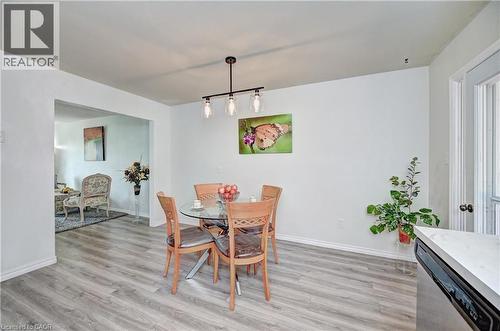 Dining area featuring wood-finish flooring, a contemporary linear chandelier, white baseboards, and an arched doorway leading to an additional living space - 92 Pinemeadow Crescent, Waterloo, ON - Indoor Photo Showing Dining Room