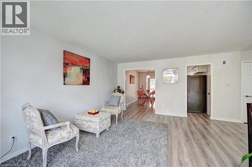 Spacious living area featuring light-toned walls, wood-finish flooring, and a textured ceiling - 92 Pinemeadow Crescent, Waterloo, ON - Indoor