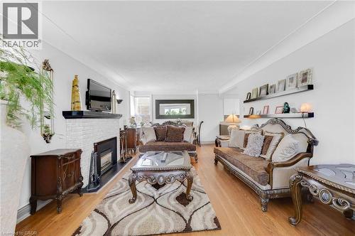 Living area with light wood-finish flooring, a white brick-style fireplace with a black mantel, and recessed lighting - 1 Galbraith Drive, Hamilton, ON - Indoor Photo Showing Living Room With Fireplace