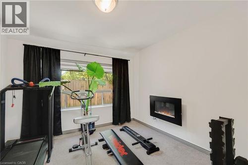 Room with wall-mounted electric fireplace, light gray carpet, and white walls - 1 Galbraith Drive, Hamilton, ON - Indoor Photo Showing Gym Room