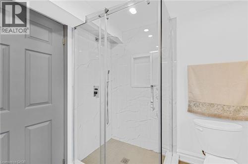 Glass-enclosed shower featuring white veined tile, a rain shower head, handheld shower fixture, and a built-in shower niche - 1 Galbraith Drive, Hamilton, ON - Indoor