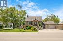 Stucco exterior residence featuring a detached single-car garage, mature front yard landscaping with tiered stone elements, and a paved driveway - 1 Galbraith Drive, Hamilton, ON  - Outdoor With Facade 